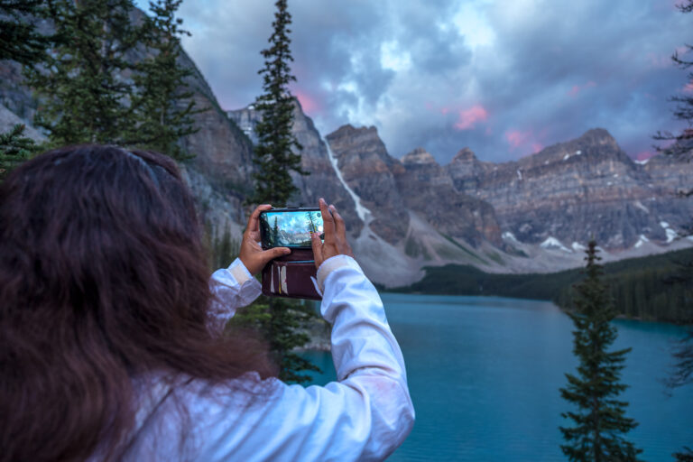 Female guest taking a photo of sunrise at Moraine Lake from the Rockpile Trail