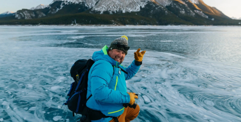 man taking photos at abraham lake of ice bubbles