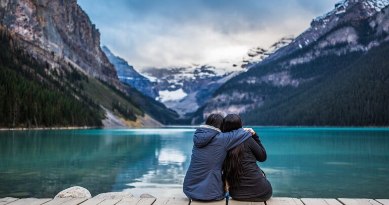 two women hugging in front of lake louise