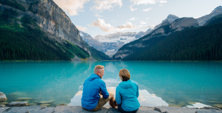couple sitting on rocks in front of moraine lake