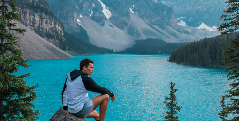 young man sitting on rocks at moraine lake