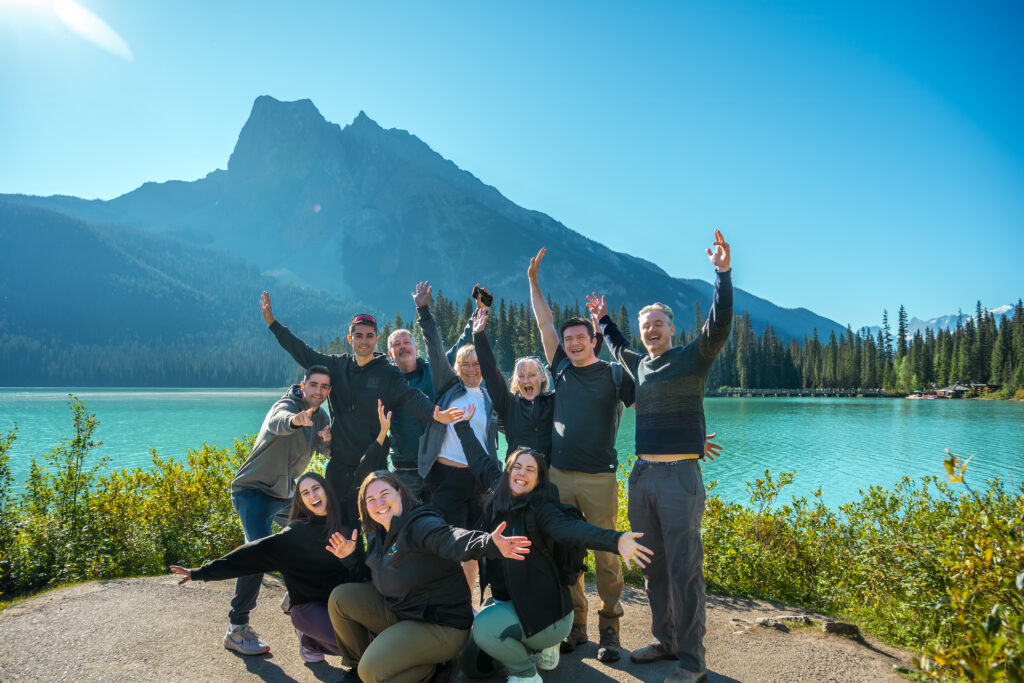 tourists laughing and posing in front of Lake Louise, Banff, with their tour guide