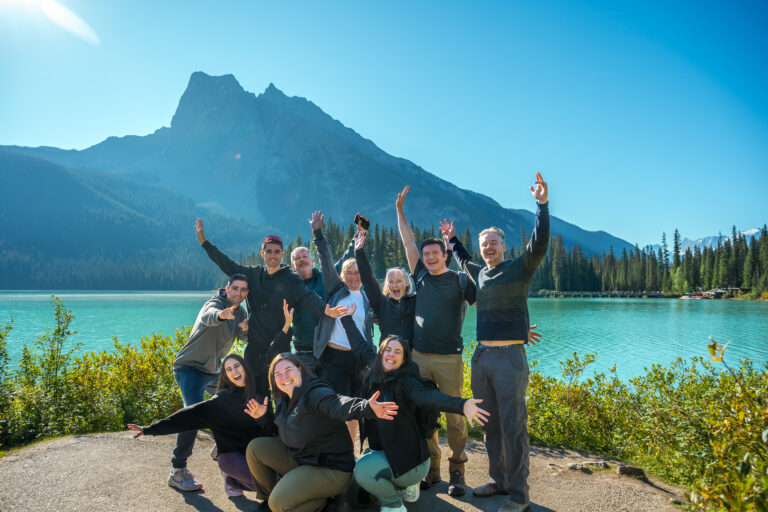 tourists laughing and posing in front of Lake Louise, Banff, with their tour guide