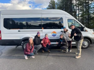 Radventures guests and guide crouched in front of tour van showing the Radventures logo.